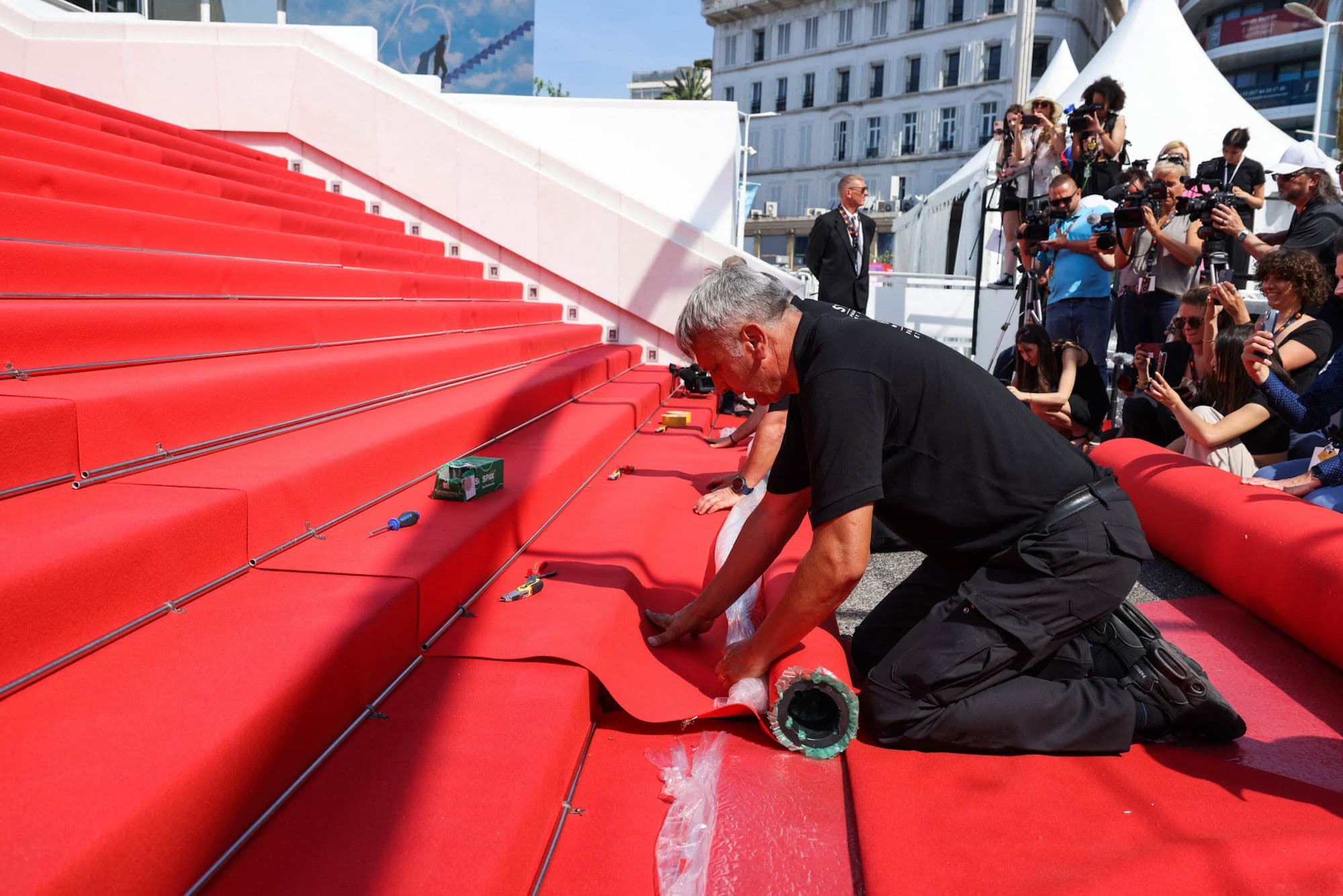Un operario del Festival de Cannes coloca la alfombra roja de la escalinata en la edición 75 de la muestra