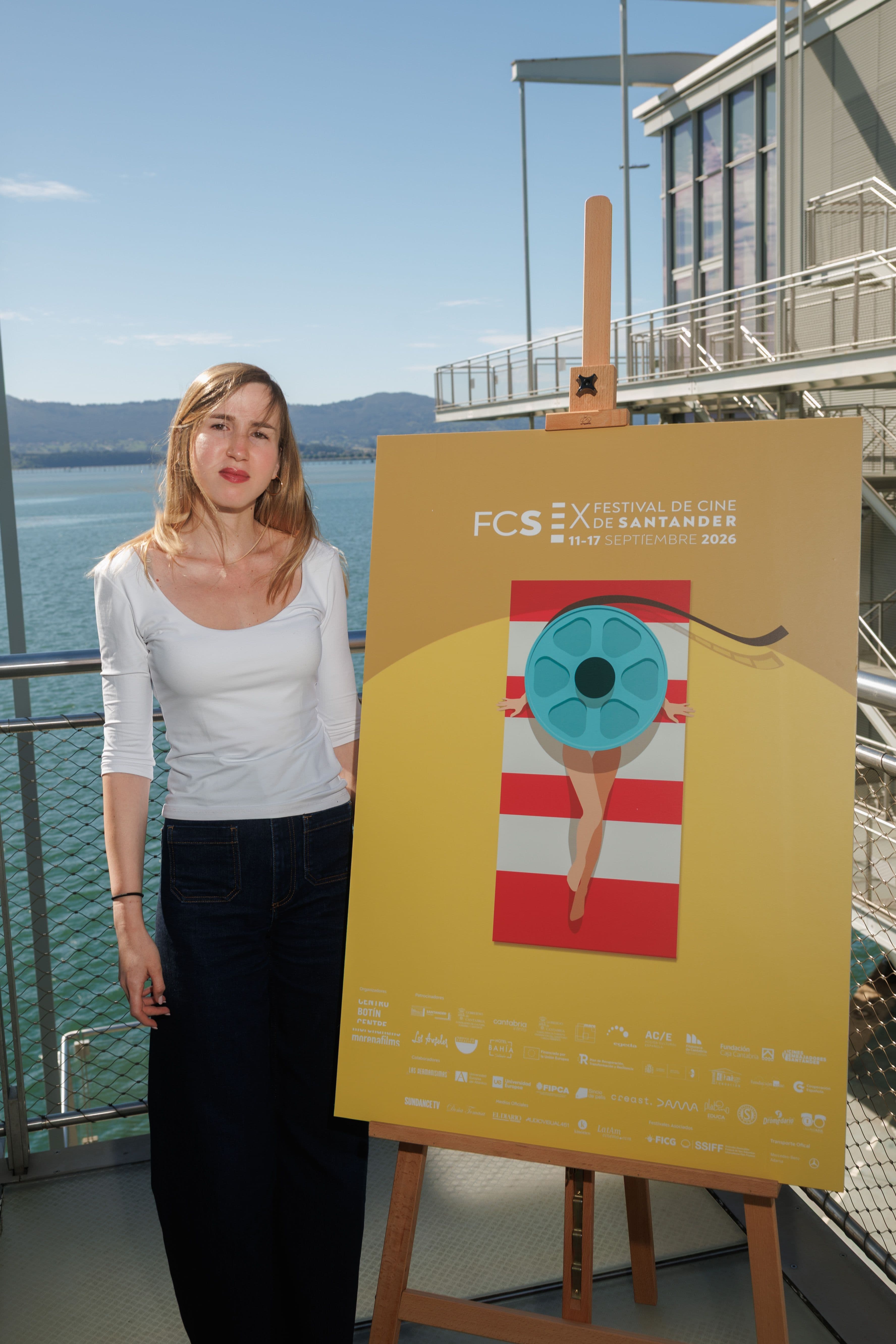 Júlia Olmo, directora del Festival de Cine de Santander, posa junto al cartel de la décima edición del certamen en septiembre de 2026
